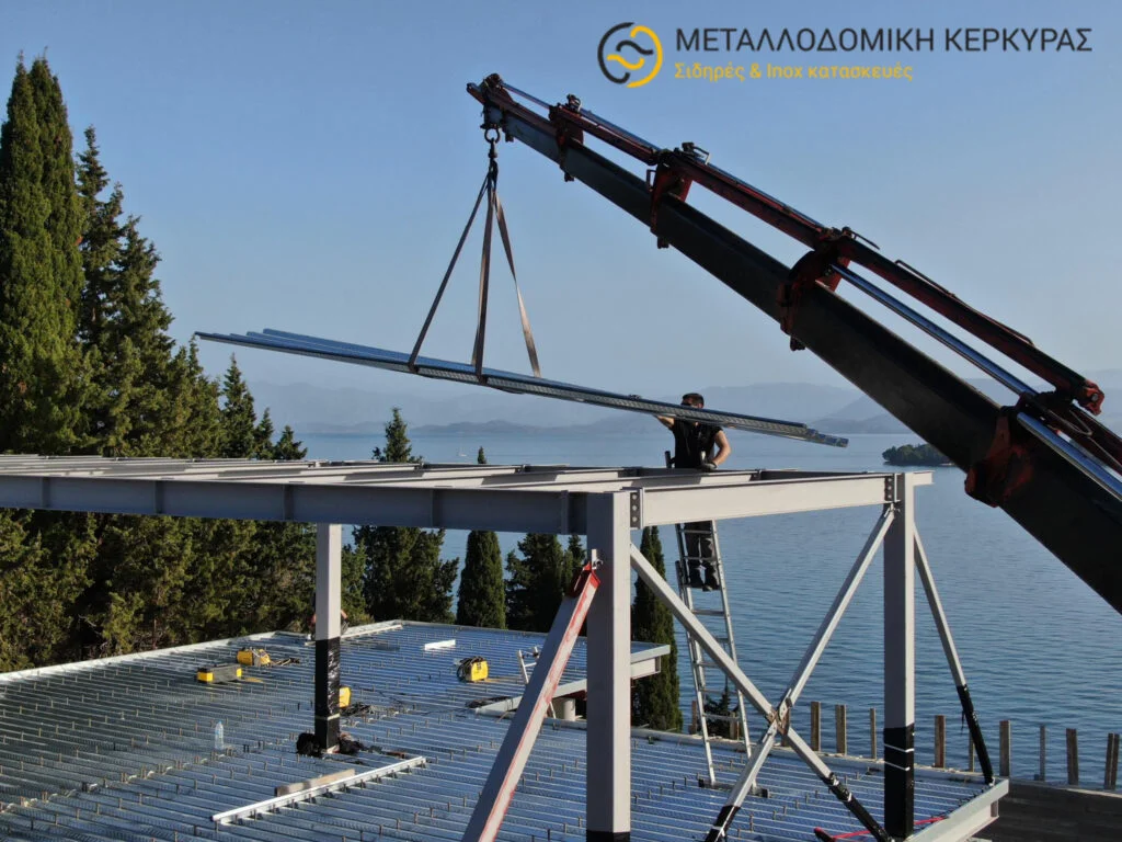 Ένας γερανός τοποθετεί μια μεταλλική δοκό σε μια μεταλλική κατασκευή σε εργοτάξιο ανέγερσης μεταλλικού κτιρίου
